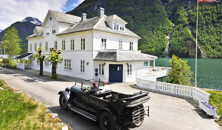 Fjaerland Fjordstove Hotell white hotel building on lake with vintage car in foreground