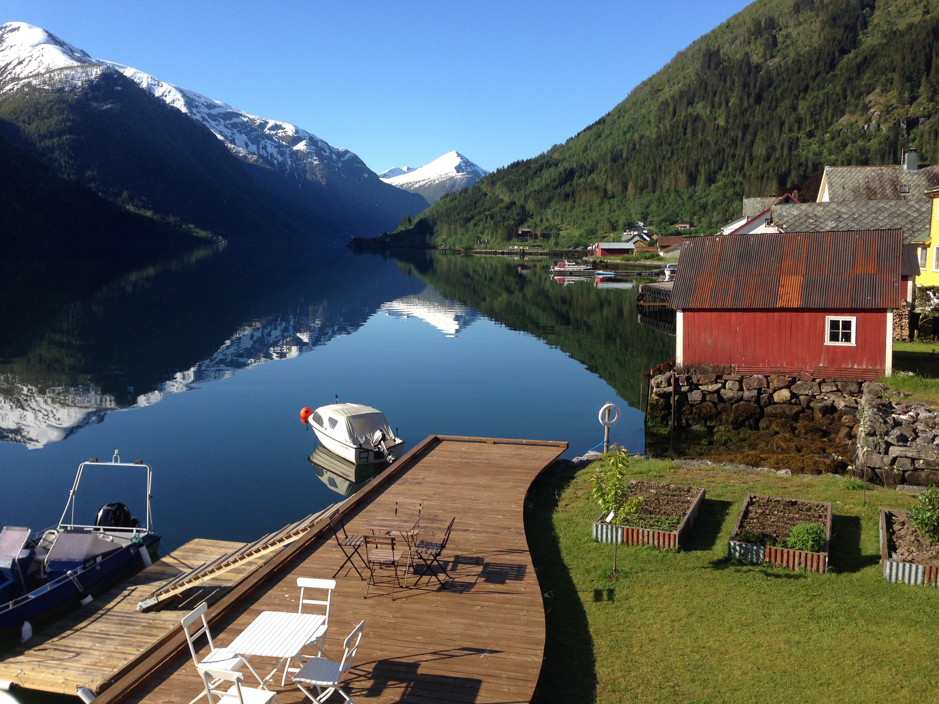 Fjaerland Fjordstove Hotell view of lake with snowy mountains and lakeside jetty with boat