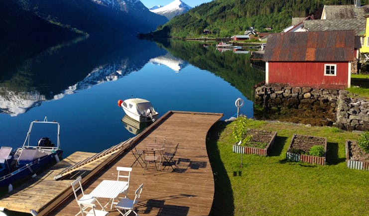 Fjaerland Fjordstove Hotell view of lake with snowy mountains and lakeside jetty with boat