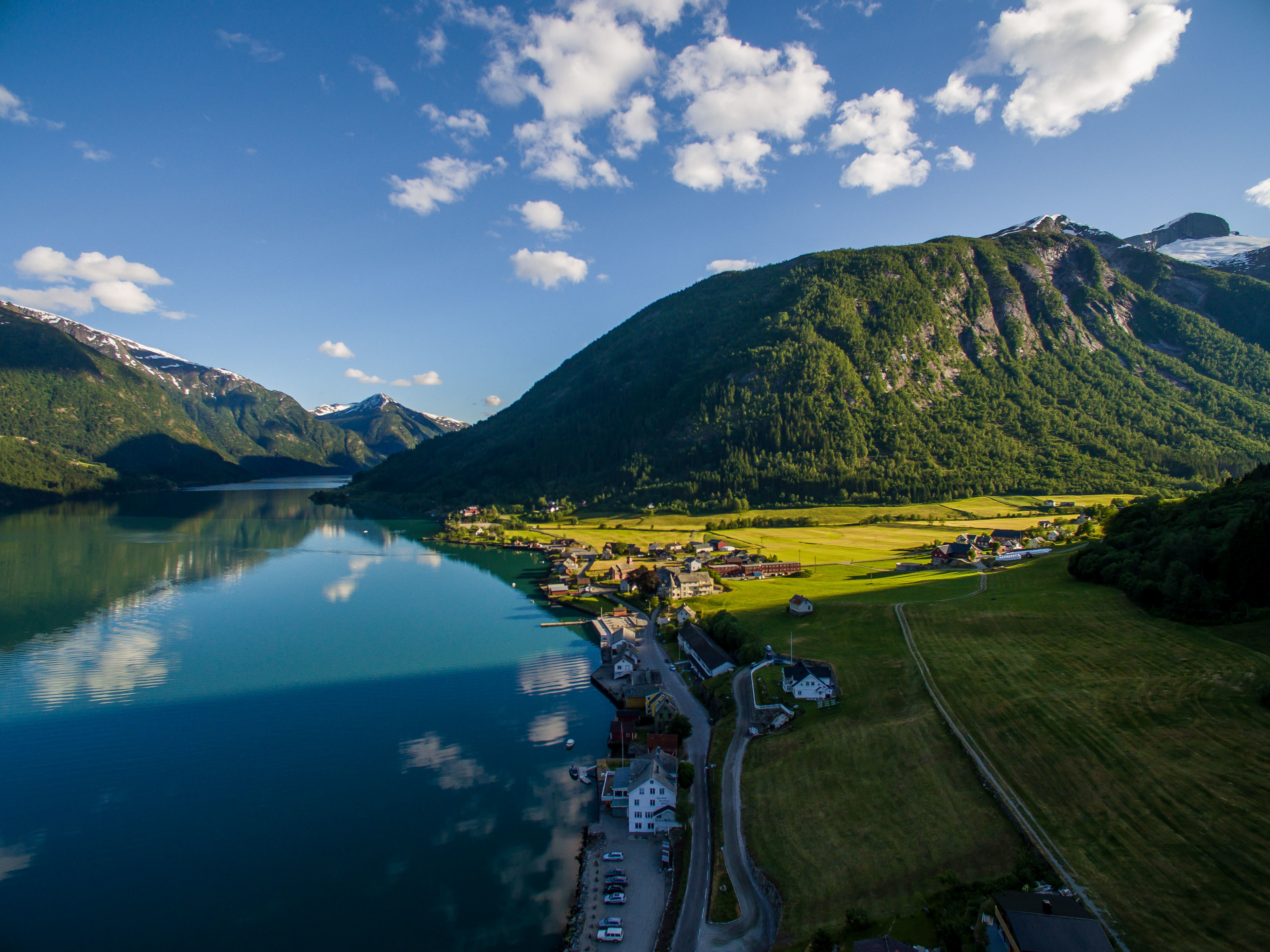 Fjaerland Fjordstove Hotell lake with green fields at side and wooden hills and mountains in distance