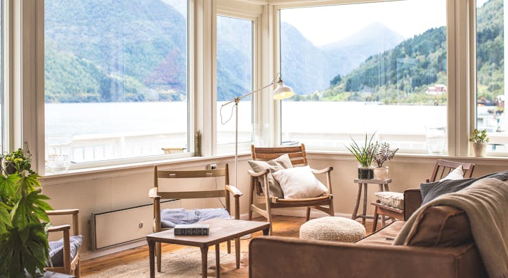 Fjaerland Fjordstove Hotell corner of room with large windows overlooking late with chairs and plants