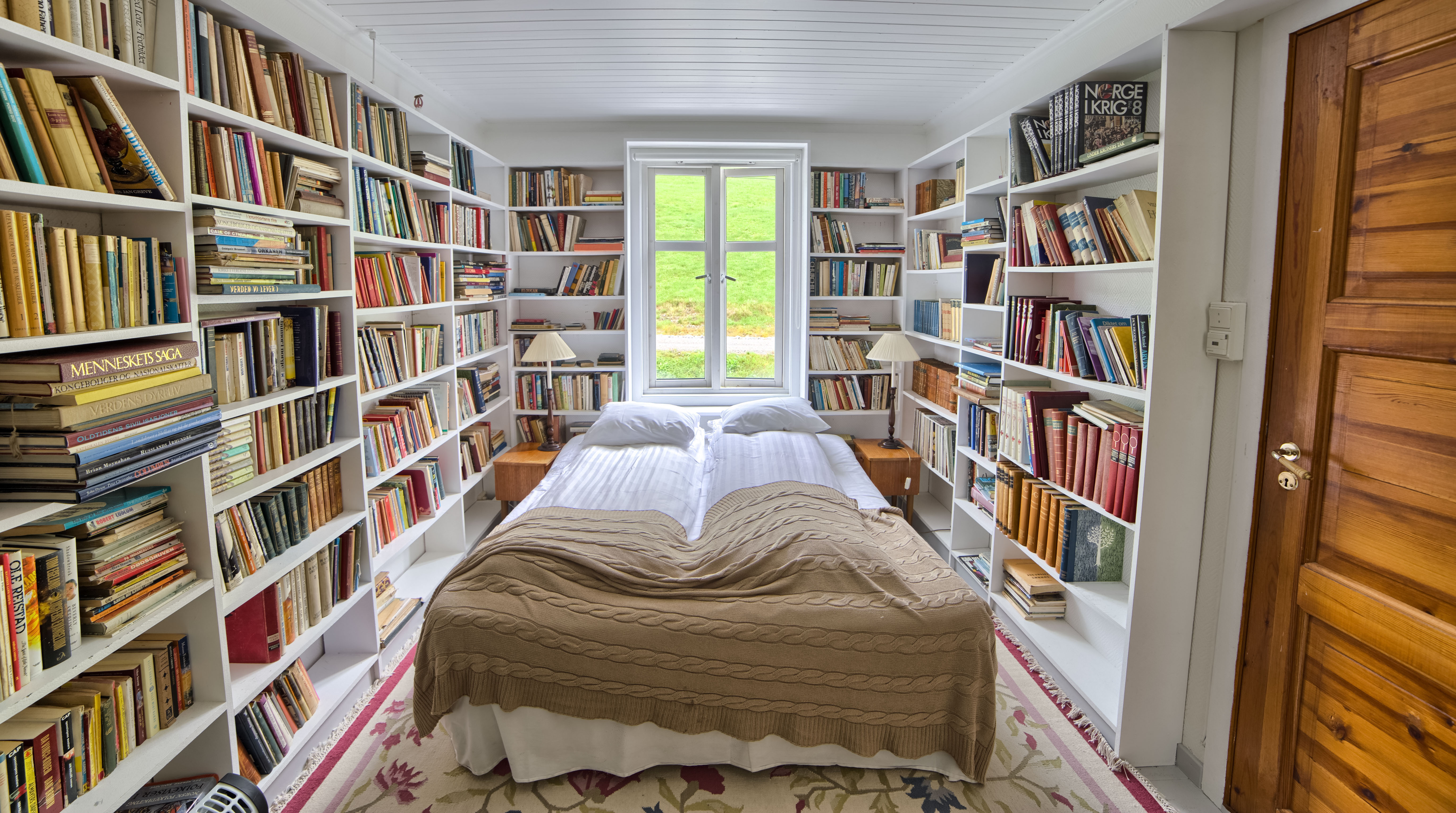 Fjaerland Fjordstove Hotell bedroom in room lined with books on white shelves
