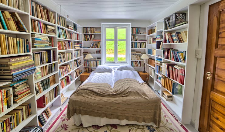 Fjaerland Fjordstove Hotell bedroom in room lined with books on white shelves