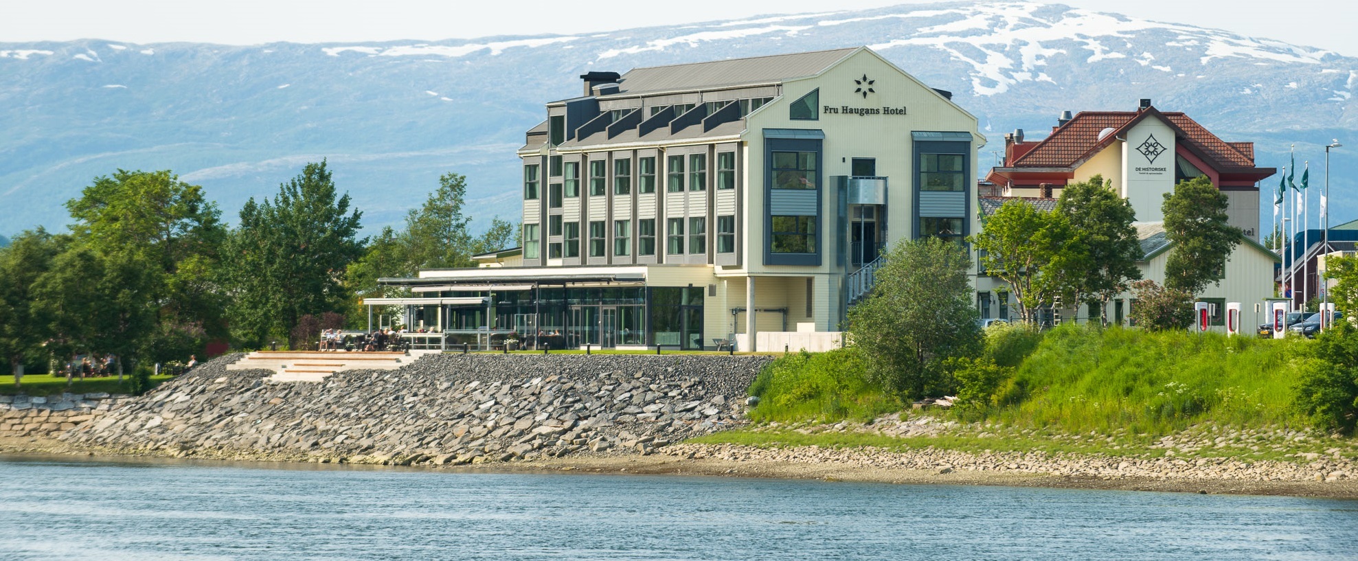 Fru Haugans Hotel Exterior on the riverside with mountains behind