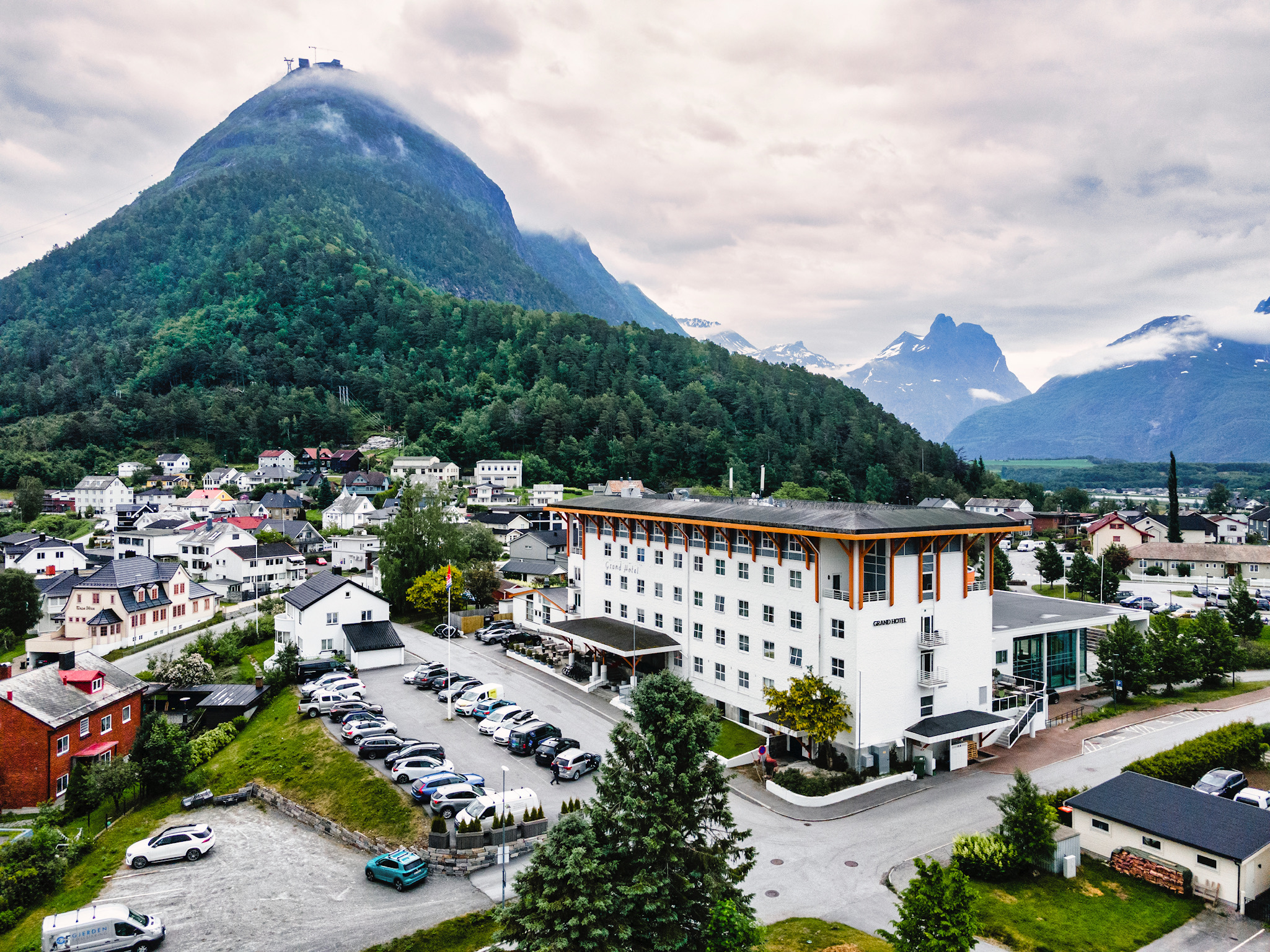 Grand Hotel Andalsnes elevated view, showing the chalet-style architecture of the hotel, the green surroundings, and the mountains behind