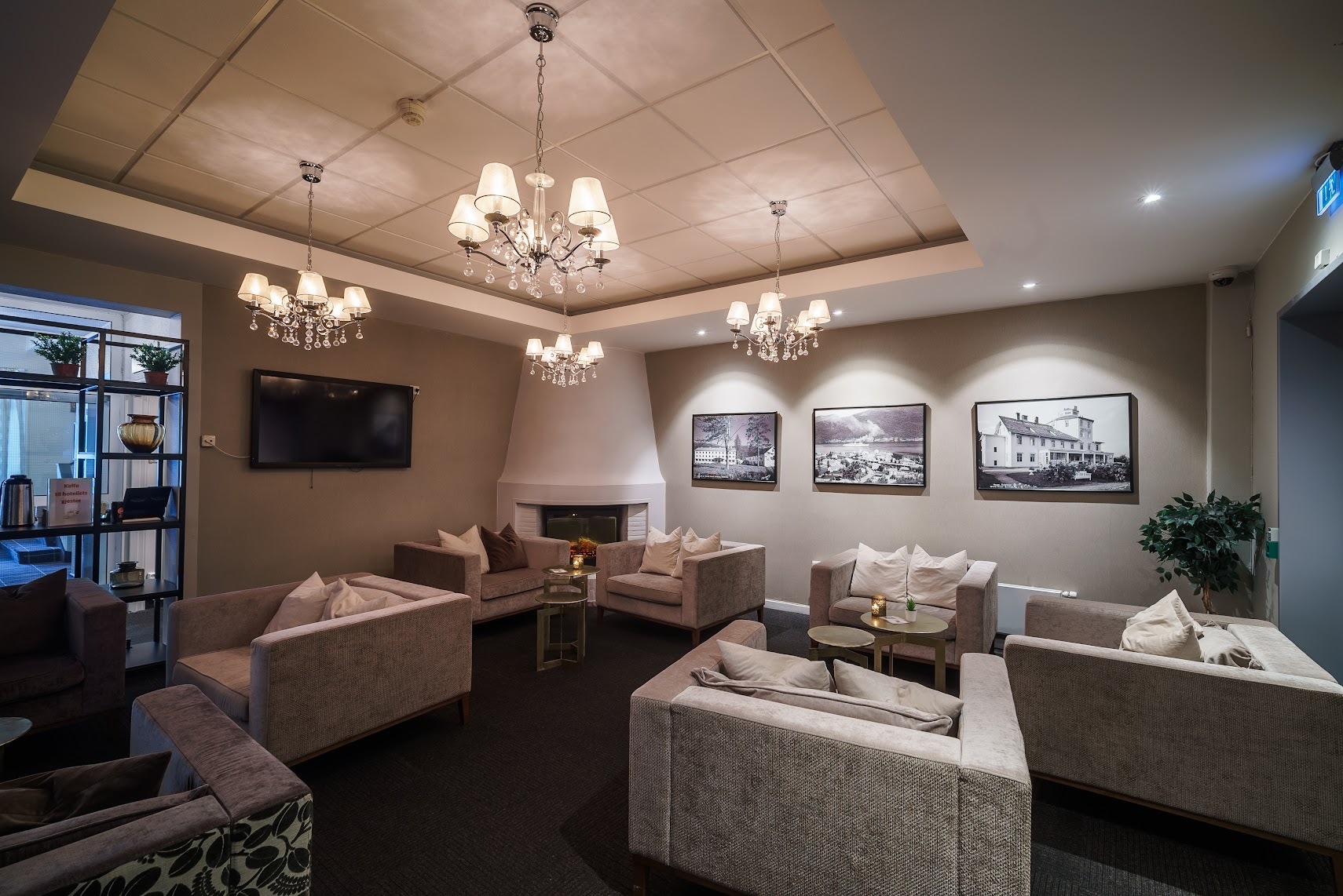 Grand Hotel Andalsnes lounge area in muted grey colours, with fireplace in the far corner and deep, low, square armchairs