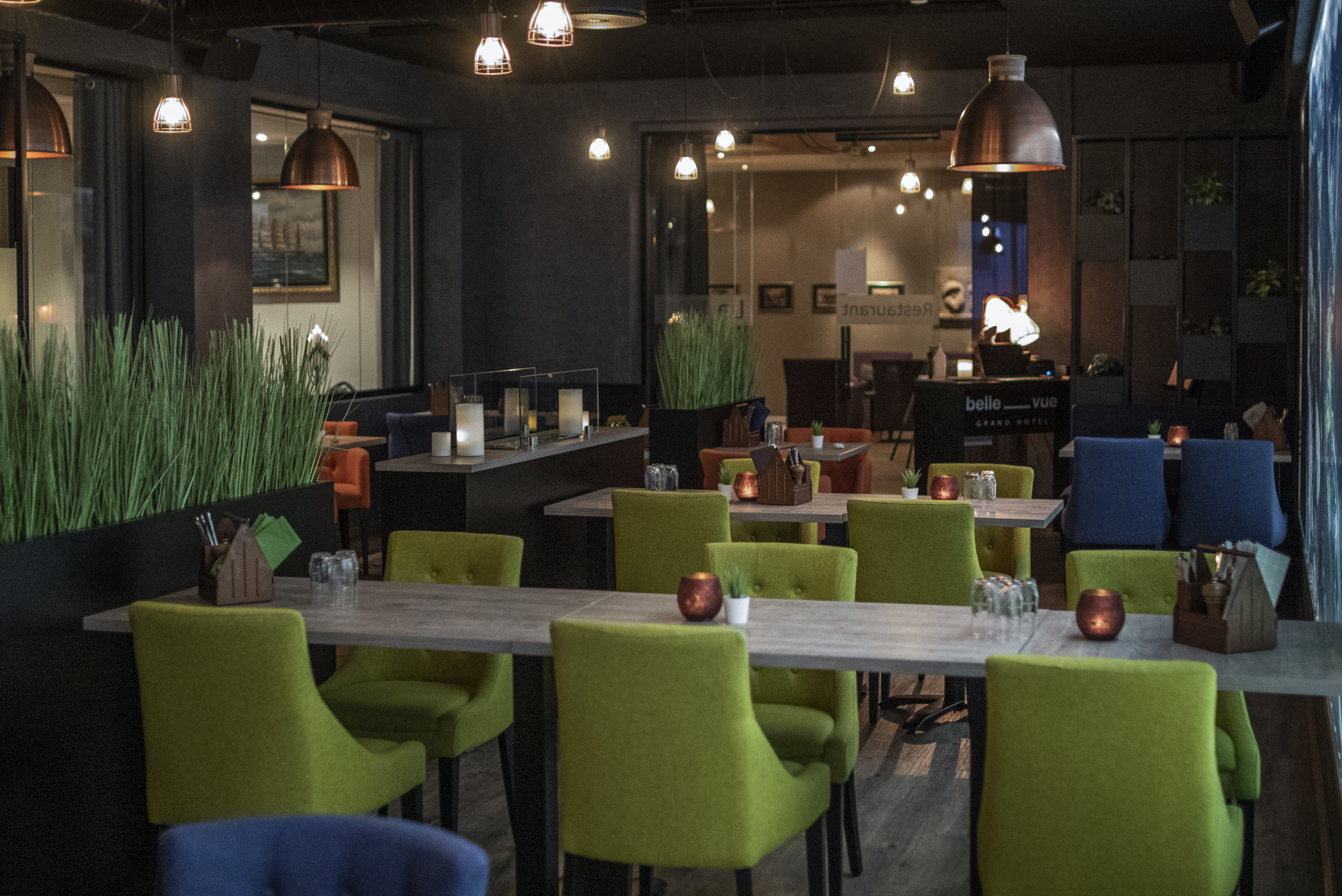 Grand Hotel Andalsnes restaurant, with dim, atmospheric lighting, green armchairs, and verdant decorations