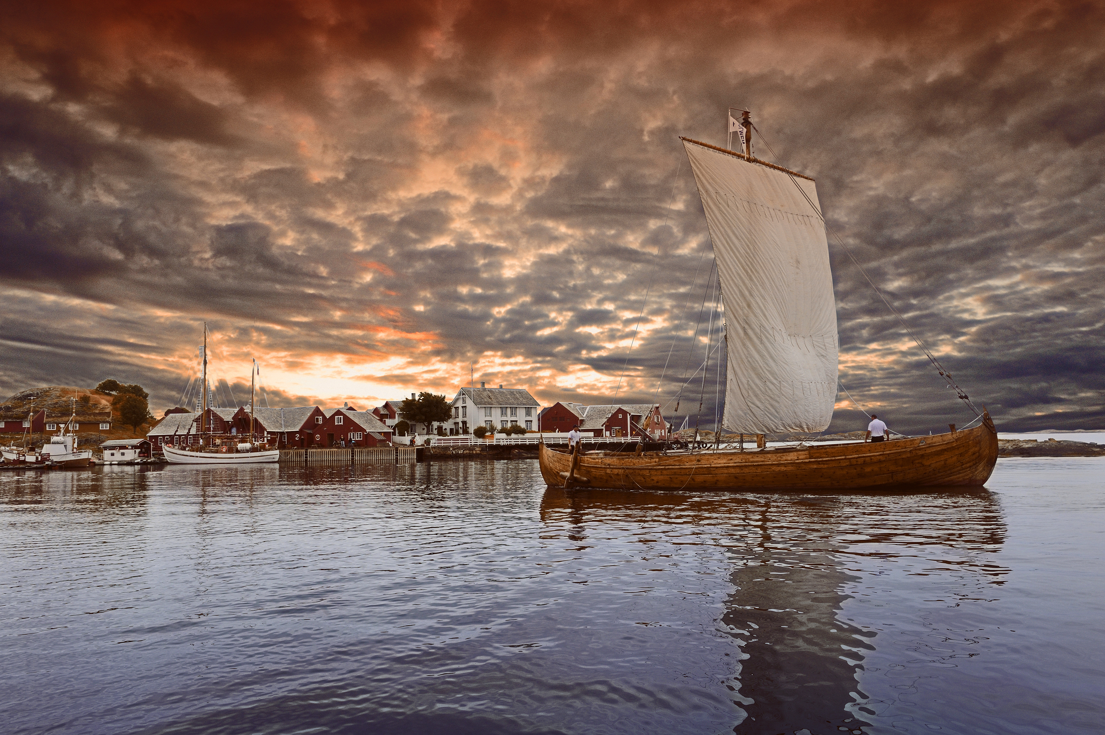 Sailing boat by island with cloudy sky