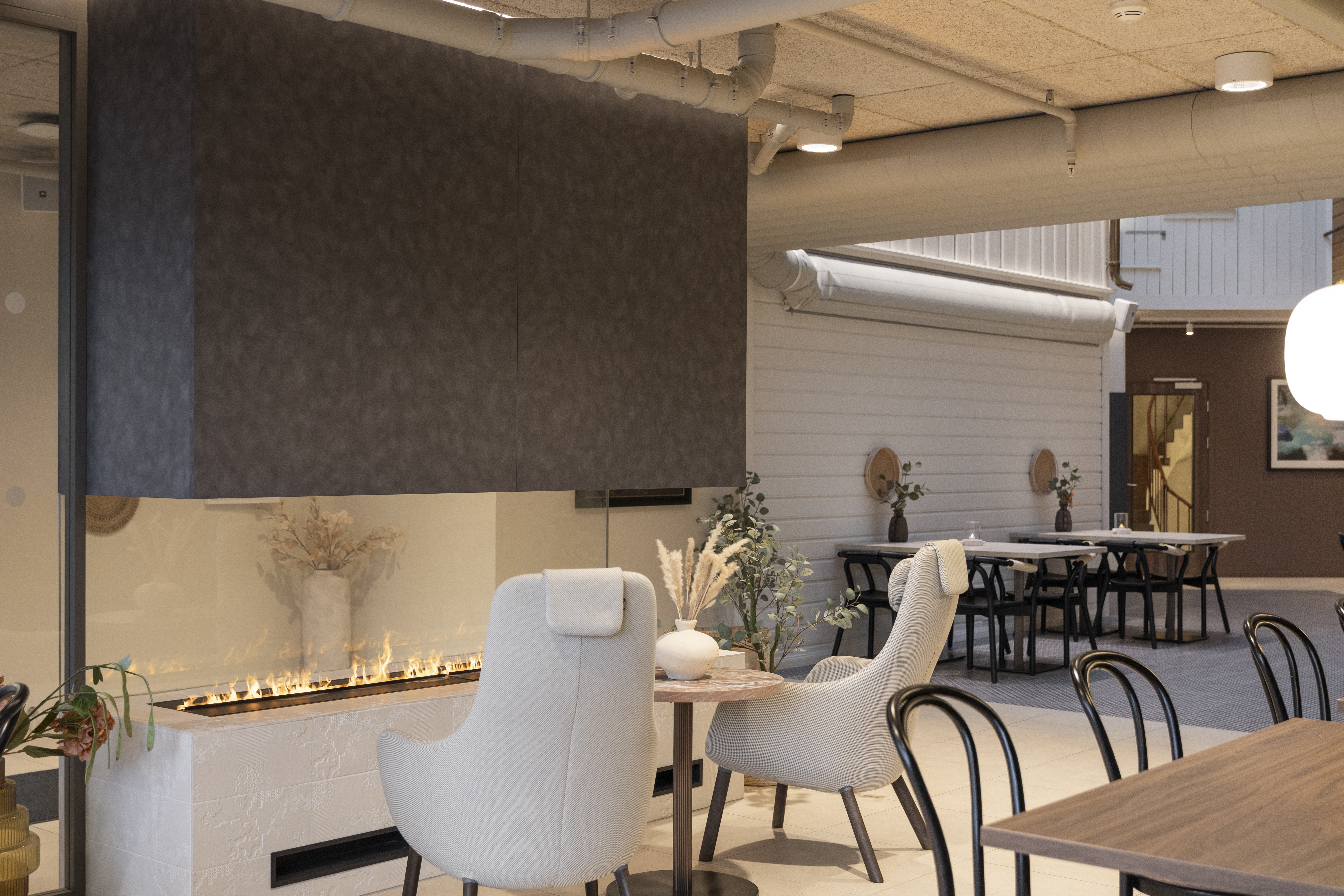 Home Hotel Grimstad Lobby with modern white chairs seated facing a minimalist monochrome fireplace