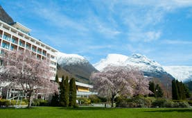 Hotel Alexandra Loen modern hotel with balconies and blossom on trees with snow on mountain tops behind