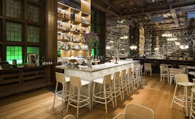 Bar with white high chairs and wooden floor at Bergen Bors