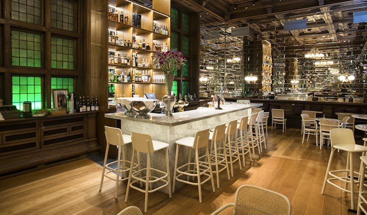 Bar with white high chairs and wooden floor at Bergen Bors