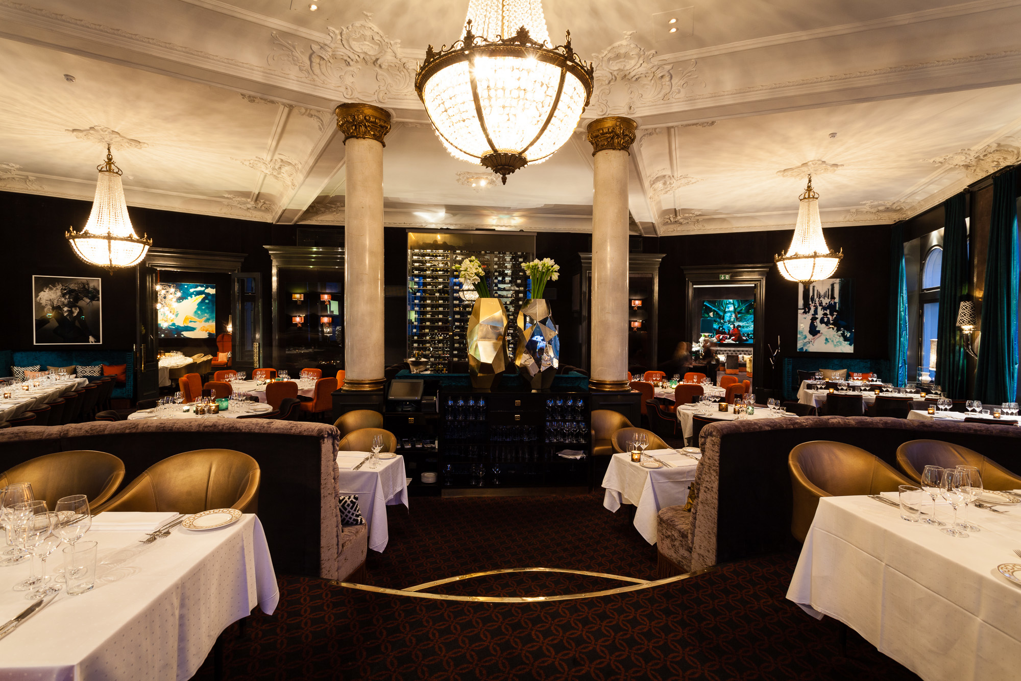Hotel Continental Oslo restaurant with dark floor and large white chandeliers