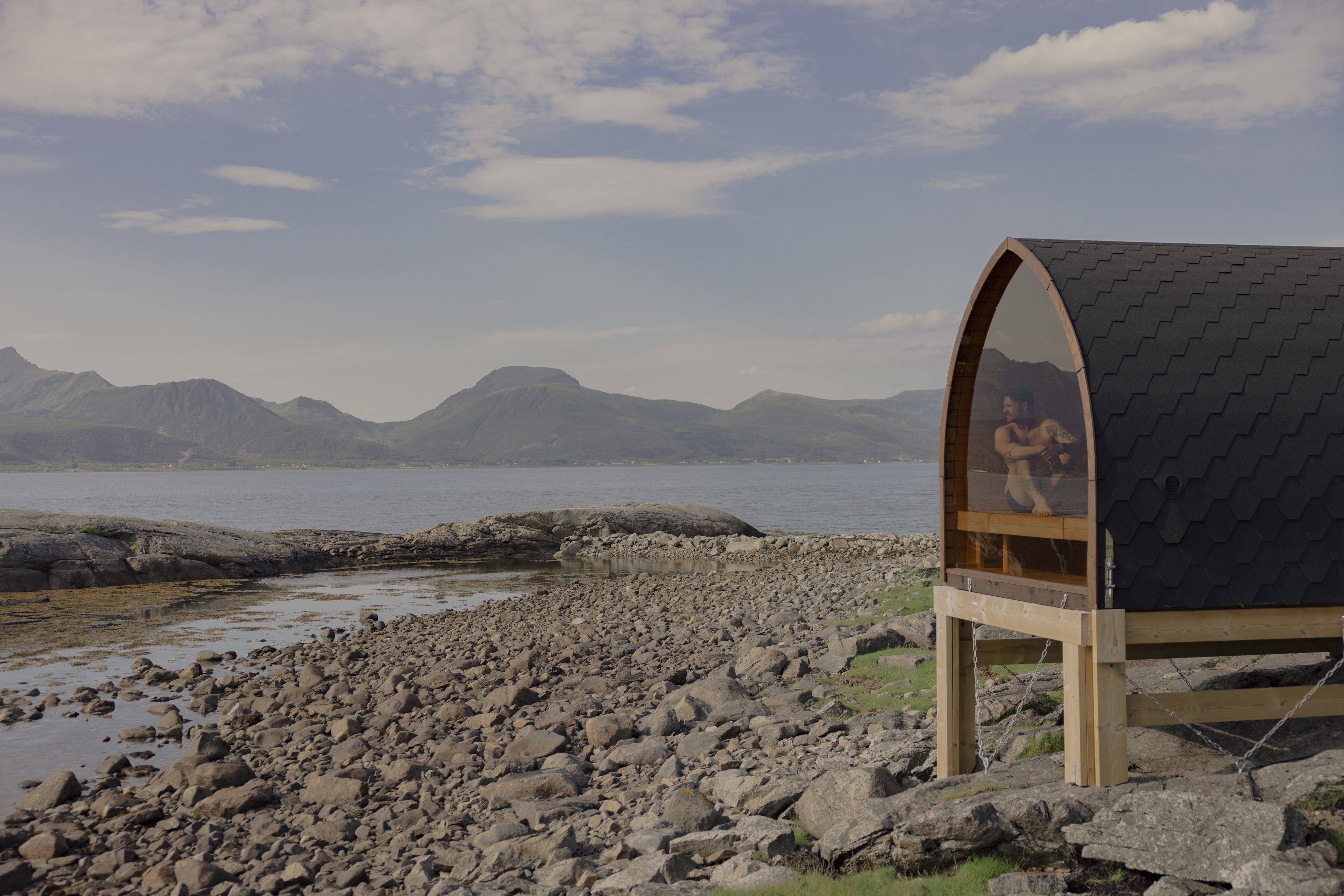 Kvitnes Gard beachfront sauna with glass wall looking out to sea across the rocky shore