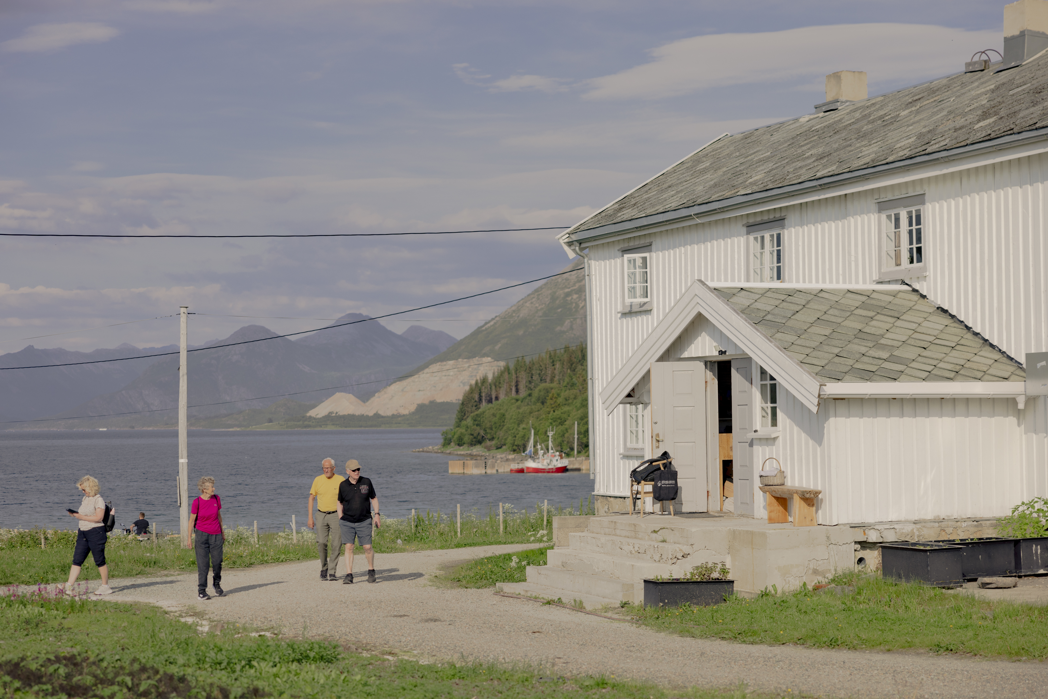 Kvitnes Gard white farmhouse entrance with the sea and cliffs behind