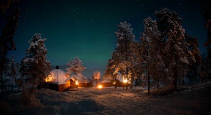 Camp fires and tents in winter evening in snow