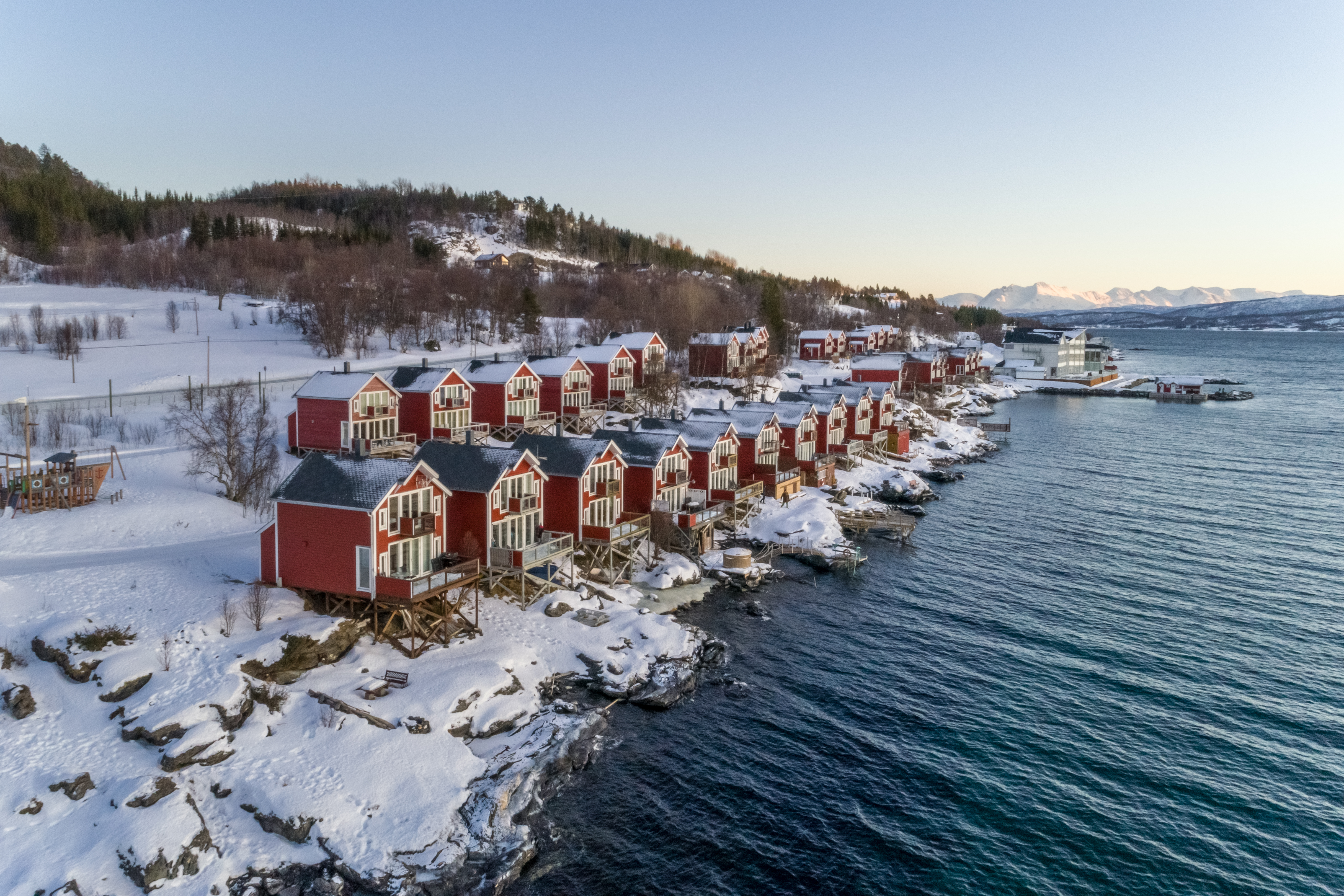 Red huts and cabins in snow on side of water