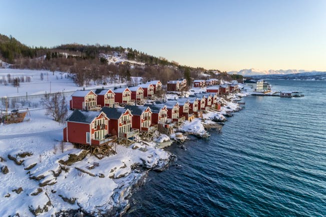 Red huts and cabins in snow on side of water