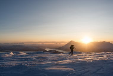 Skier on snow with sun behind