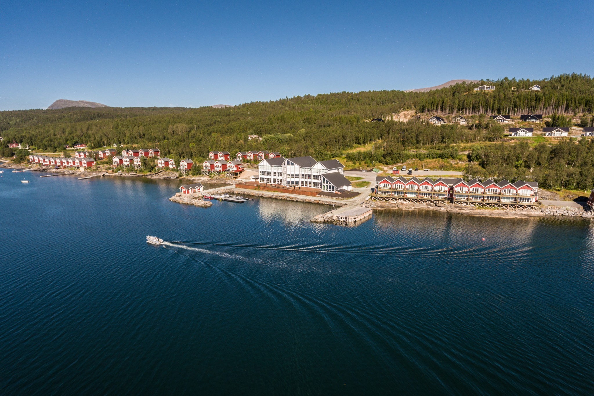 Hotel buildings on edge of blue water with trees behind