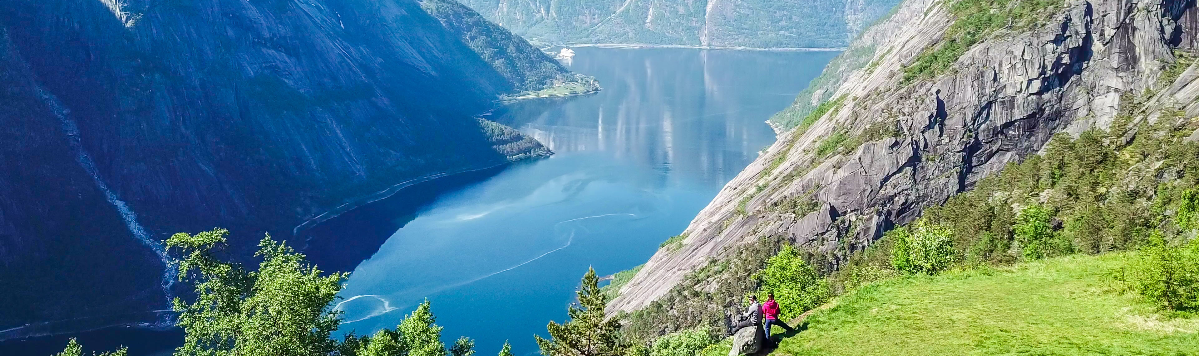 Couple overlooking the Eidfjord with steep cliffs and deep blue waters