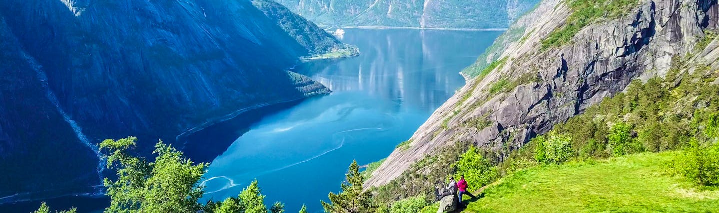 Couple overlooking the Eidfjord with steep cliffs and deep blue waters