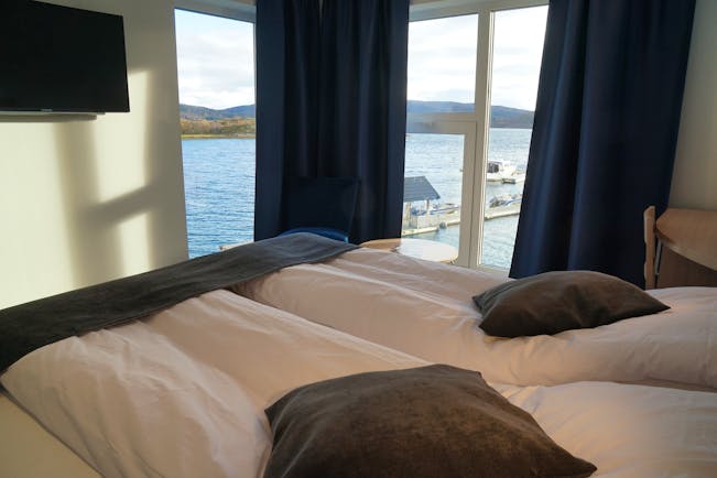 Senja Fjordhotell modern bedroom in grey and white with corner windows and views of water