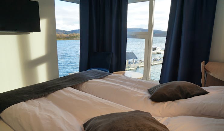 Senja Fjordhotell modern bedroom in grey and white with corner windows and views of water