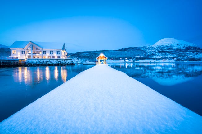 Senja Fjordhotell illuminated white building on water in snow