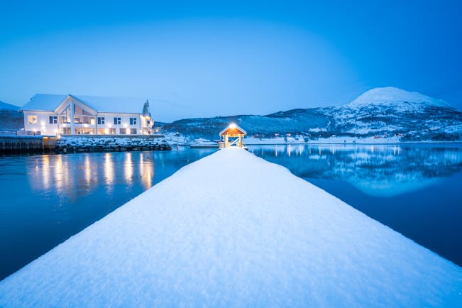 Senja Fjordhotell illuminated white building on water in snow