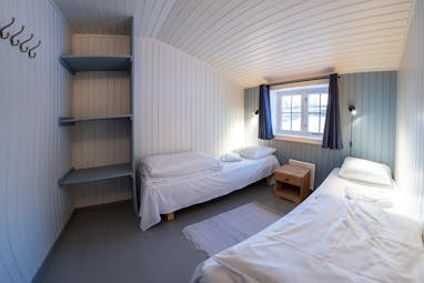 Svinoya Rorbuer bedroom with white wooden walls and small window