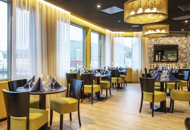 Thon Hotel Harstad restaurant with brown tables and yellow seats to chairs