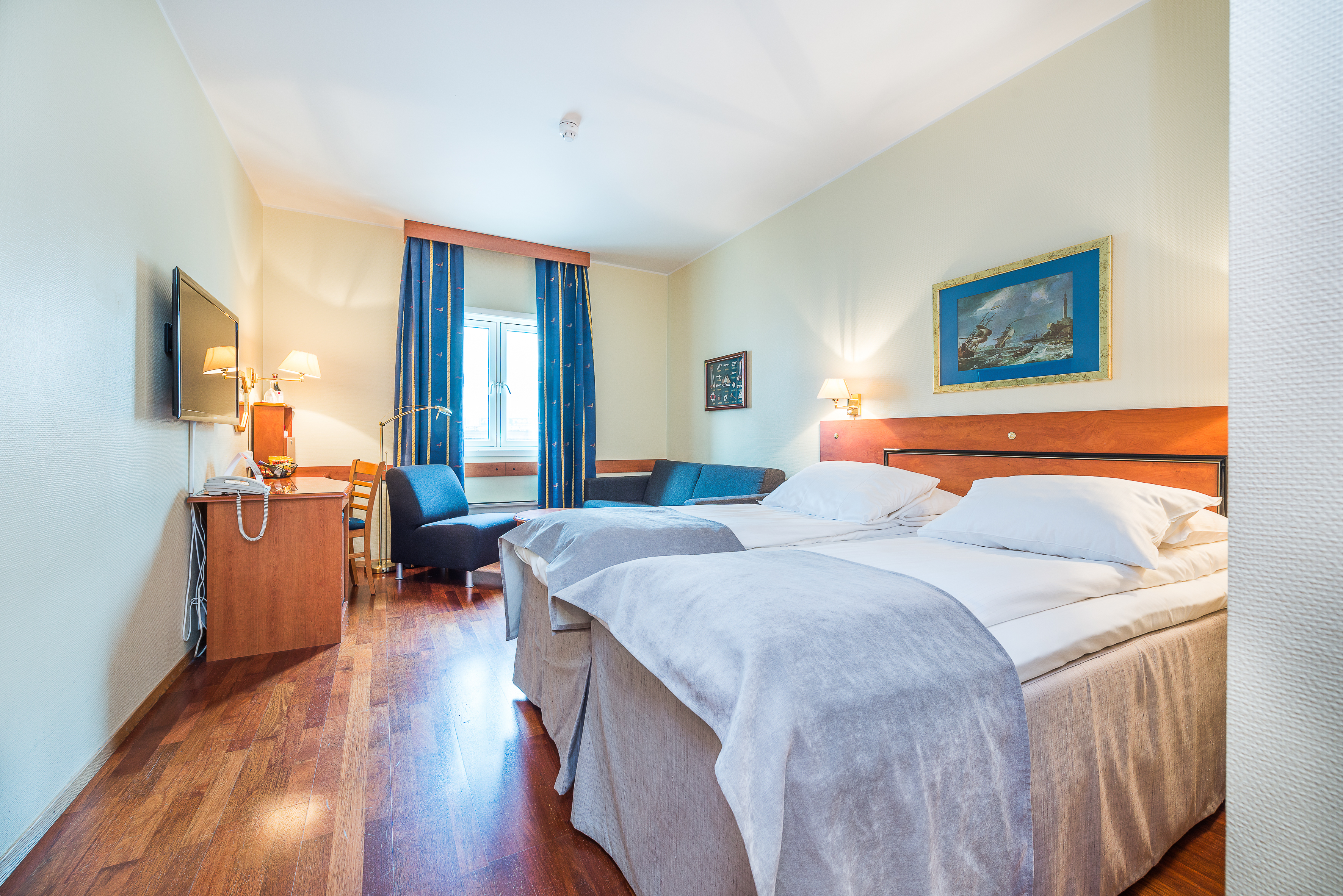 Thon Hotel Harstad room with white walls and bed with blue curtains and chairs