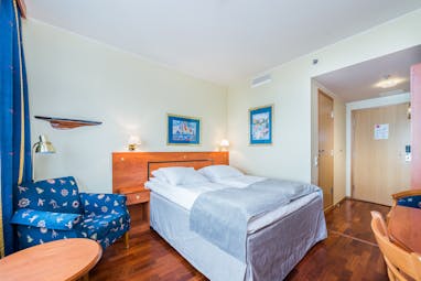 Thon Hotel Harstad bedroom with wooden floor, blue chair and white ad grey bed coverings