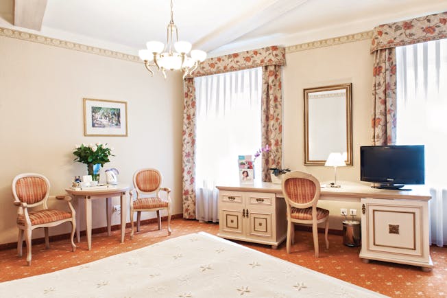 Bedroom with dressing table, television, a chandelier and curtains 