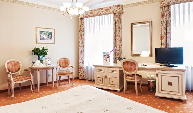 Bedroom with dressing table, television, a chandelier and curtains