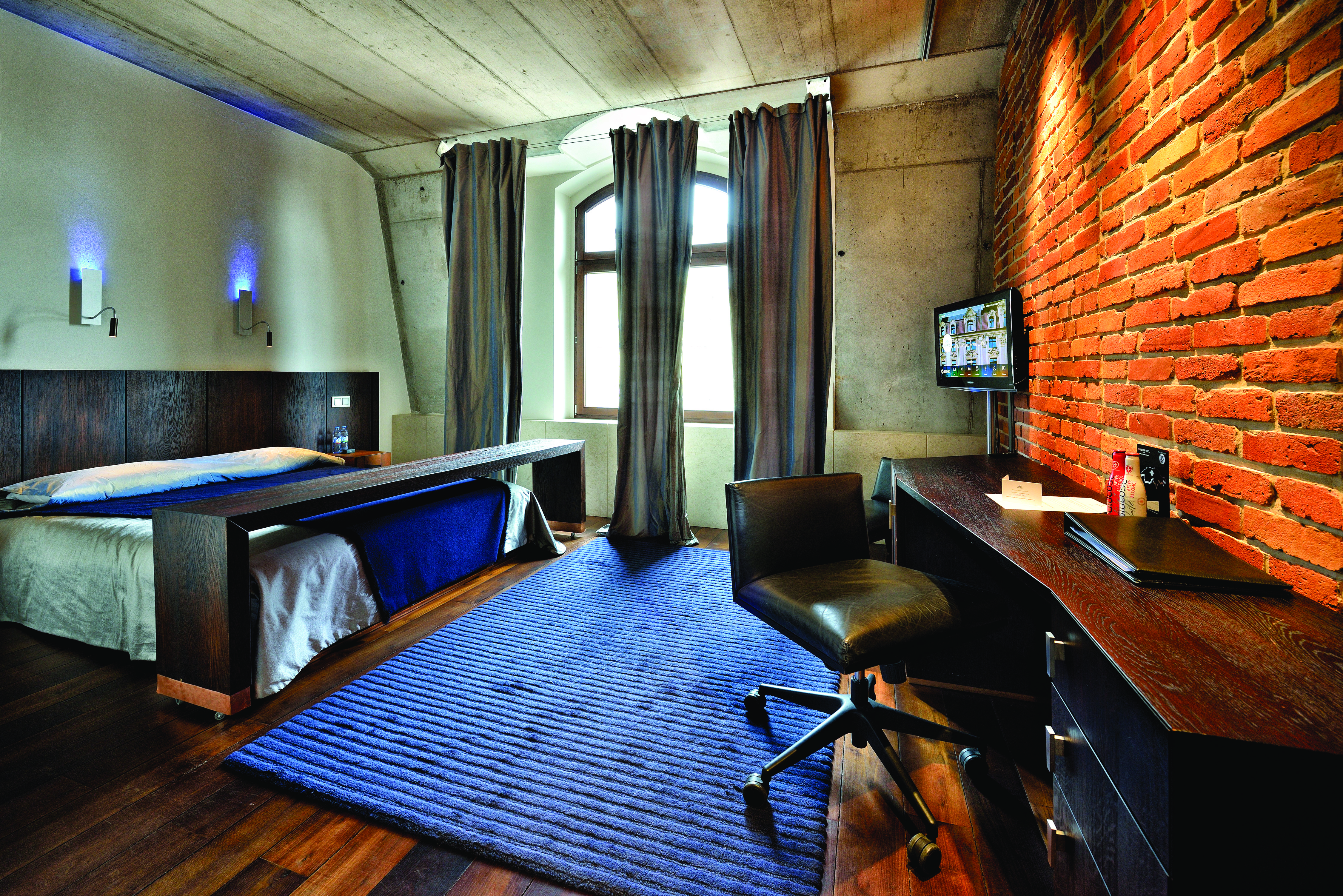 Hotel Monopol Wroclaw standard double room with stone ceiling and walls, an arched window, large double bed and a purple and black colour scheme