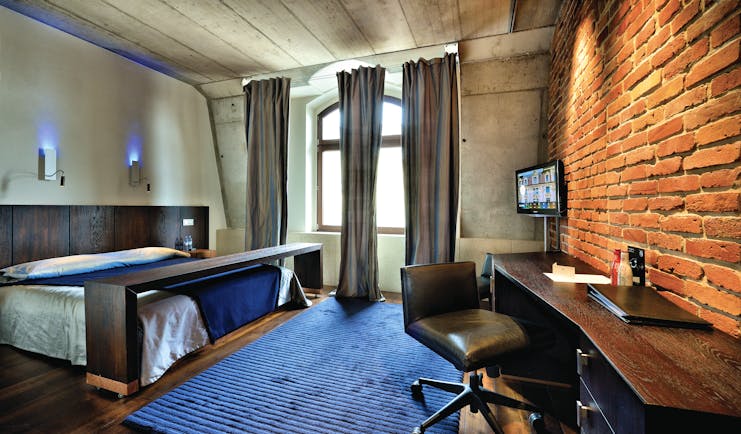 Hotel Monopol Wroclaw standard double room with stone ceiling and walls, an arched window, large double bed and a purple and black colour scheme