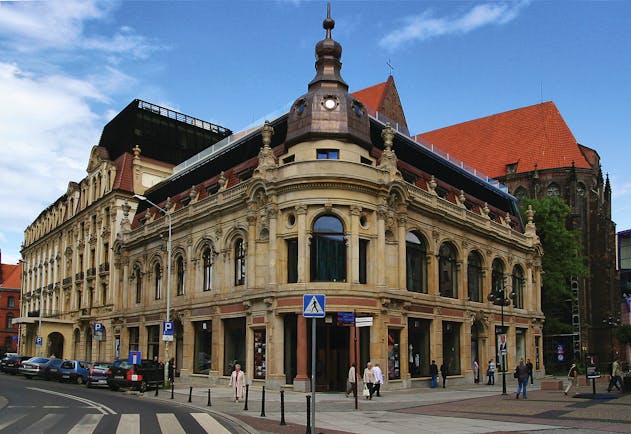 Hotel Monopol Wroclaw exterior large building with large windows and statues on the roof