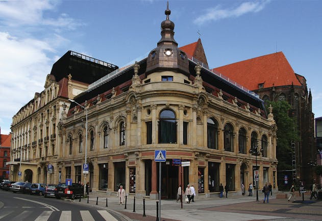 Hotel Monopol Wroclaw exterior large building with large windows and statues on the roof