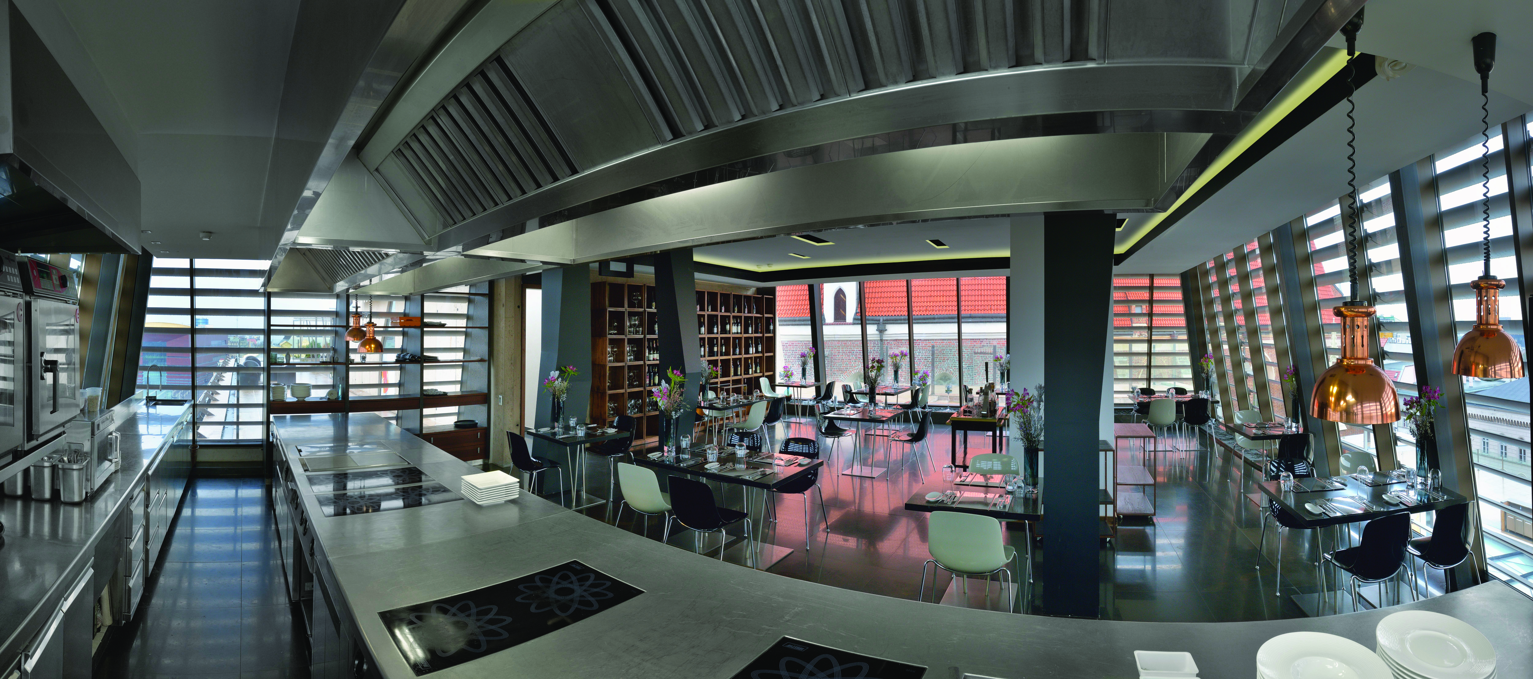 Hotel Monopol Wroclaw restaurant Aquario with a light grey colour scheme, large rectangular windows replacing the walls and dining tables filling the room