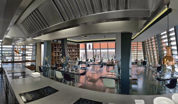 Hotel Monopol Wroclaw restaurant Aquario with a light grey colour scheme, large rectangular windows replacing the walls and dining tables filling the room