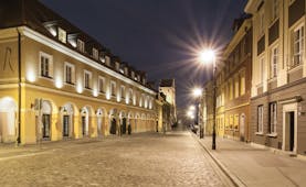 Mamaison Le Regina Warsaw exterior yellow building with archways and lamps on a cobbled street