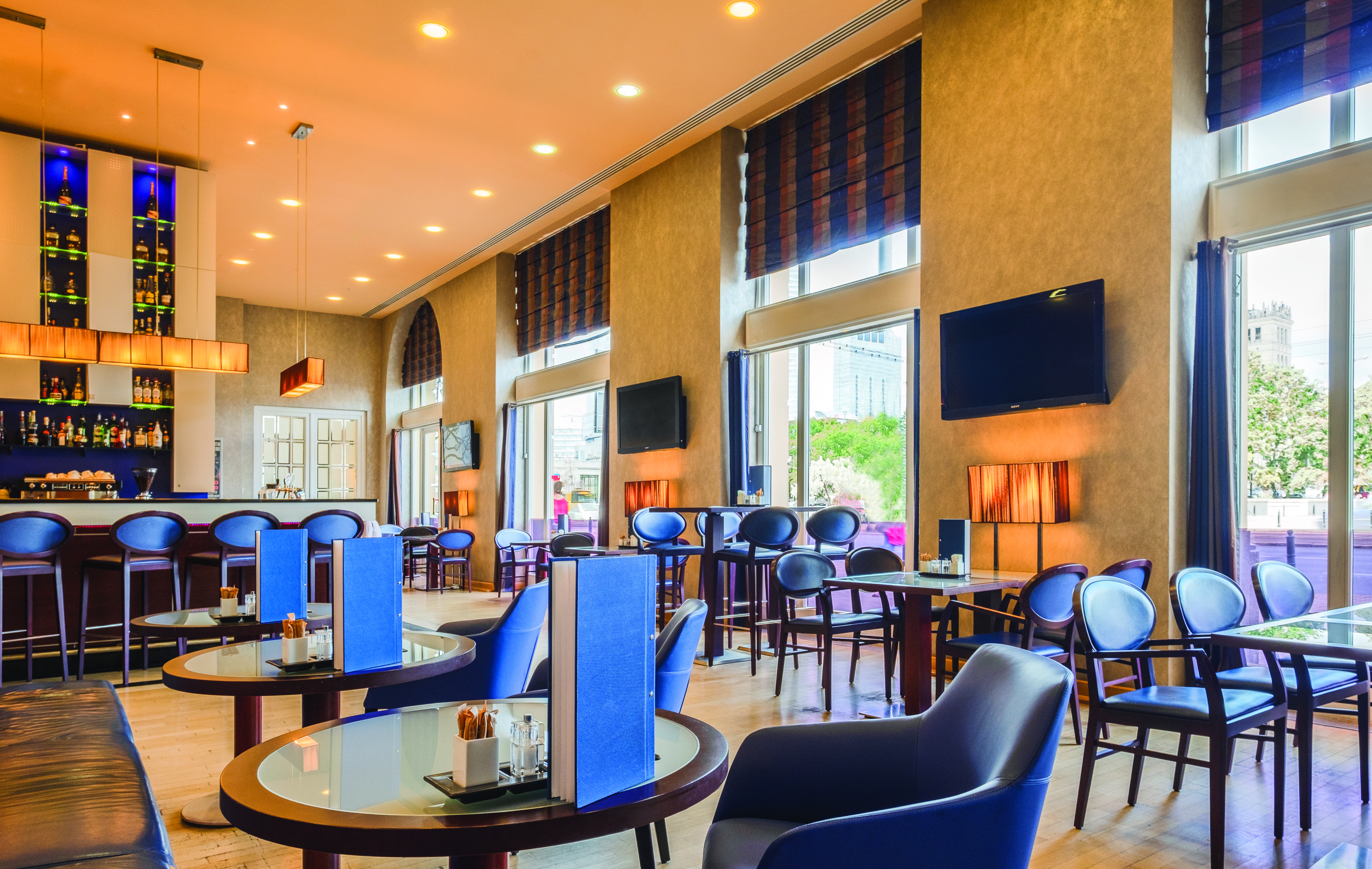Polonia Palace Hotel dining area with tables set out in a large room with multiple blue chairs and multiple large double doors 