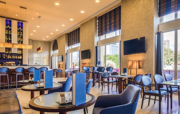 Polonia Palace Hotel dining area with tables set out in a large room with multiple blue chairs and multiple large double doors 