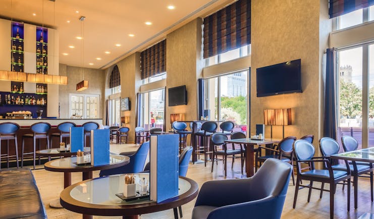 Polonia Palace Hotel dining area with tables set out in a large room with multiple blue chairs and multiple large double doors