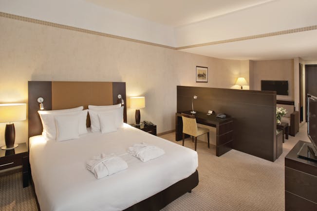 Polonia Palace Hotel junior suite with double bed, desk, television and brown and beige colour scheme