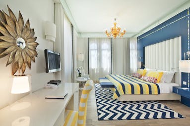 View of the Bela Vita Hotel & Spa Character room with a double bed and television decorated in yellow and navy