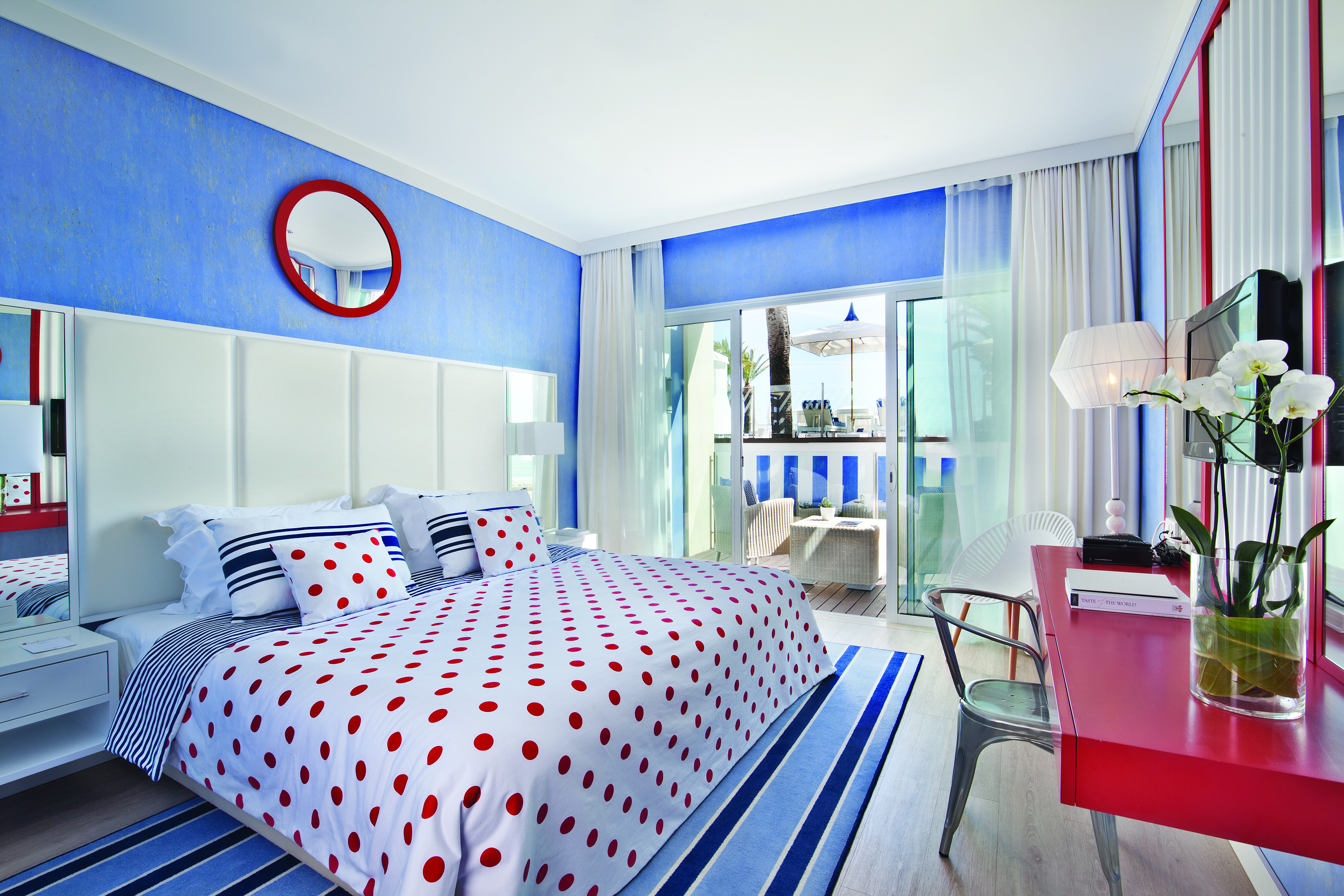 Deluxe room at the Bela Vista Hotel & Spa, decorated in blue and red with double doors leading out to a private patio area