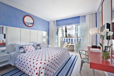 Deluxe room at the Bela Vista Hotel & Spa, decorated in blue and red with double doors leading out to a private patio area